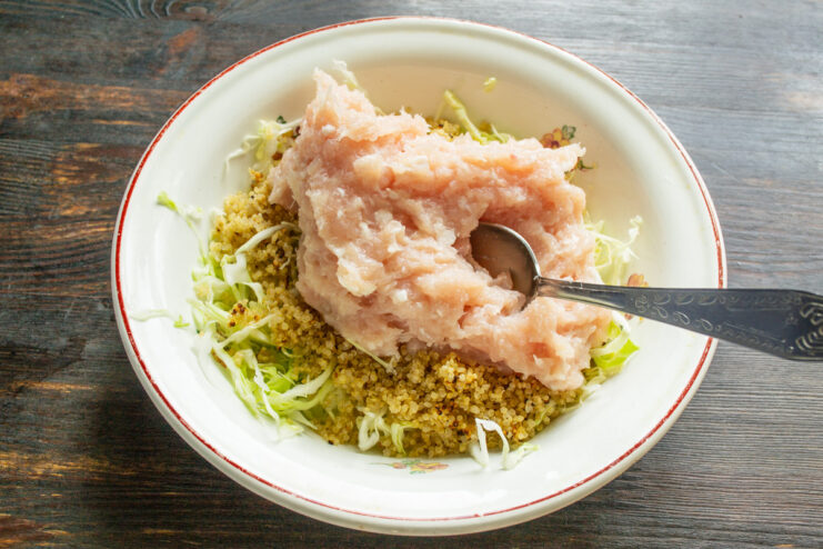 Combining ground chicken with cabbage and quinoa Ground chicken is added to the bowl with cabbage and quinoa.