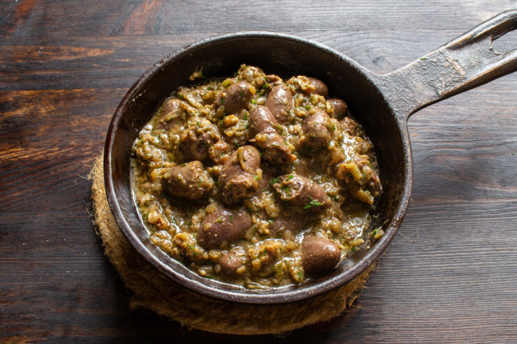 The finished chicken hearts in walnut sauce, ready to be served. A serving of chicken hearts in walnut sauce in a bowl, garnished with dill.