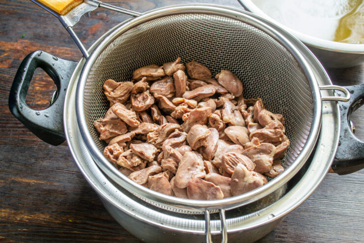 Step 4: Draining the Cooked Chicken Hearts Cooked chicken hearts being drained in a metal colander in a sink.