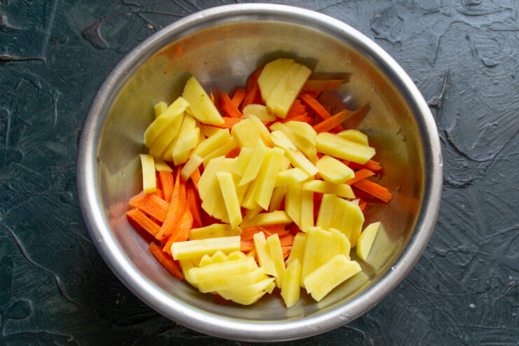 Chopping fresh vegetables for the chicken and spelt soup Freshly chopped carrots, potatoes, and bell peppers on a cutting board.