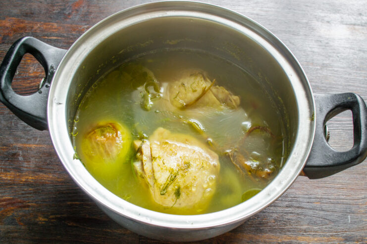 Simmering Chicken Thighs for a Rich Broth Chicken thighs simmering in a pot with herbs to create a flavorful broth for the soup.