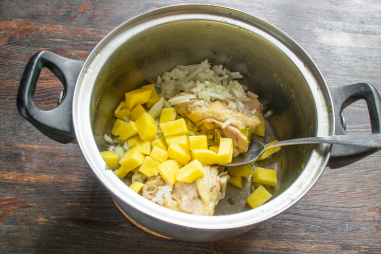 Adding Diced Potatoes to the Soup Pot Diced potatoes being added to the pot with chicken and onions.