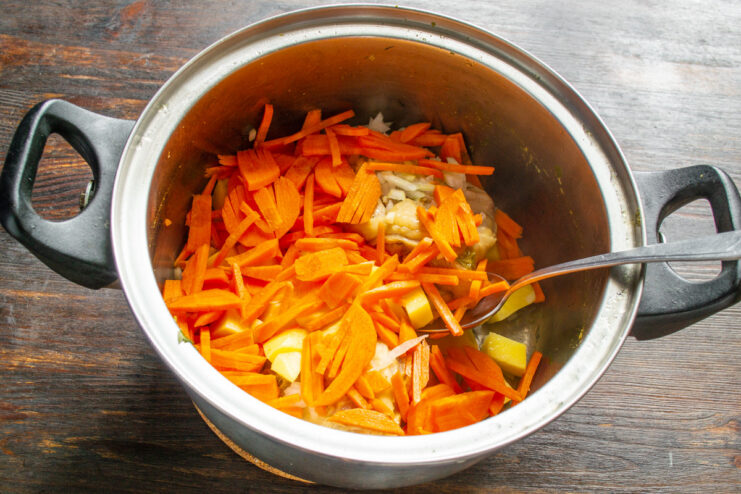 Julienning Carrots for the Chicken Soup A close-up of carrots being thinly sliced or julienned on a cutting board.