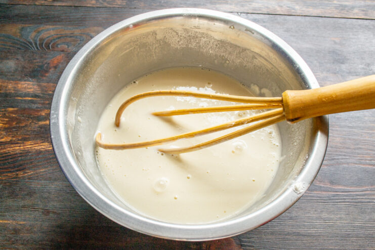 How to Make Perfect Crepe Batter from Scratch A bowl with ingredients for crepe batter being mixed with a whisk.