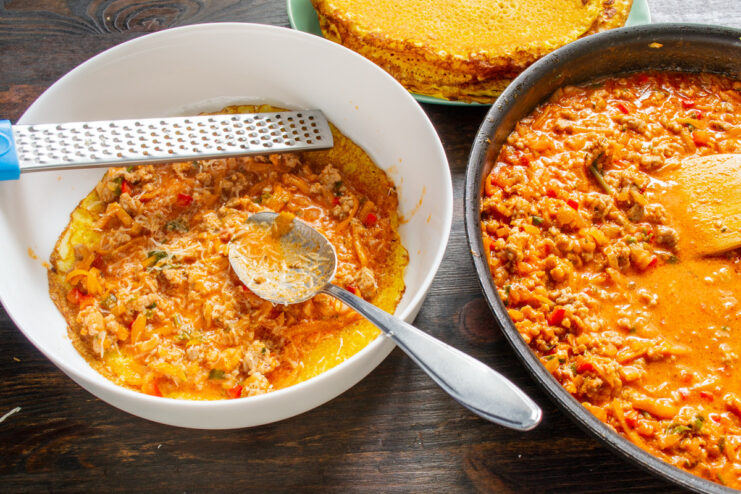 Spreading the Savory Meat Sauce Over a Crepe Layer Meat sauce being spread over a crepe in a baking dish.