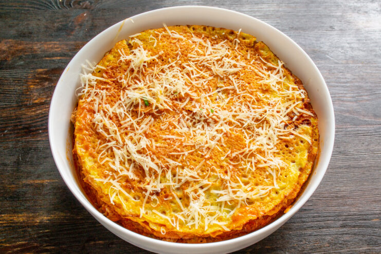 Layering Crepes, Sauce, and Cheese to Build the Lasagna A multi-layered crepe lasagna being assembled in a baking dish.