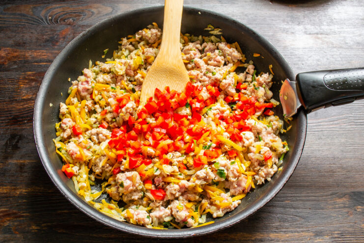 Incorporating Bell Peppers for Sweetness and Color Diced bell peppers being added to the meat and vegetable mixture in a pan.