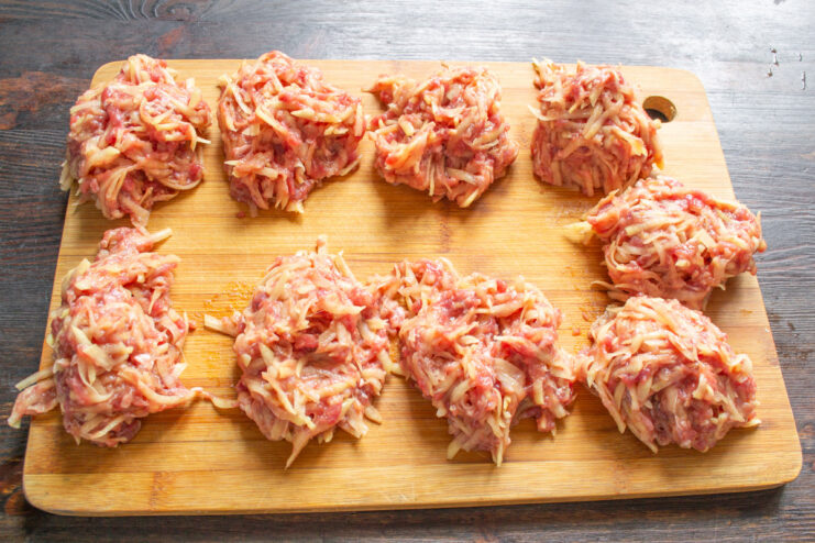 Portioning the Kolduny for Even Cooking The prepared potato and meat mixture divided into several equal portions on a cutting board.