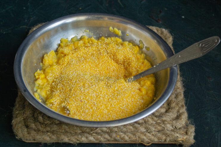 Adding dry ingredients to the corn mixture Adding corn flour and grits to the blended corn mixture in a bowl.