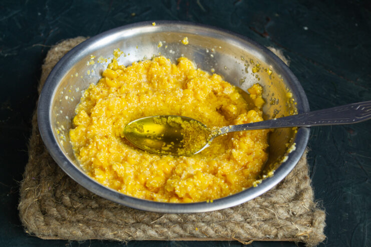 Mixing the corn fritter batter Pouring olive oil into the corn fritter batter in a glass bowl.