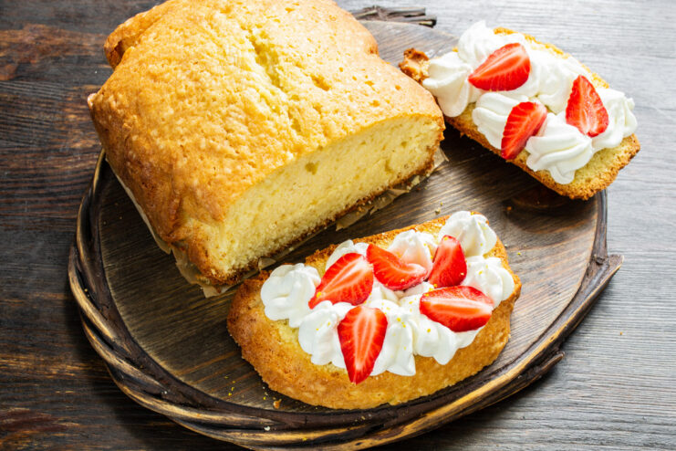 Serving the lemon pound cake with whipped cream and fresh berries. A slice of lemon pound cake topped with whipped cream and a fresh strawberry.