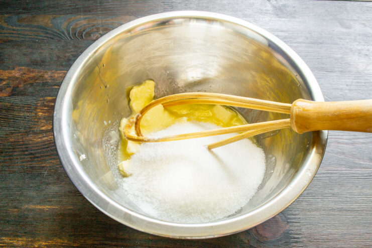Creaming butter and sugar until light and fluffy for the cake batter. A whisk mixing butter and sugar in a bowl to create a creamy base for the pound cake.