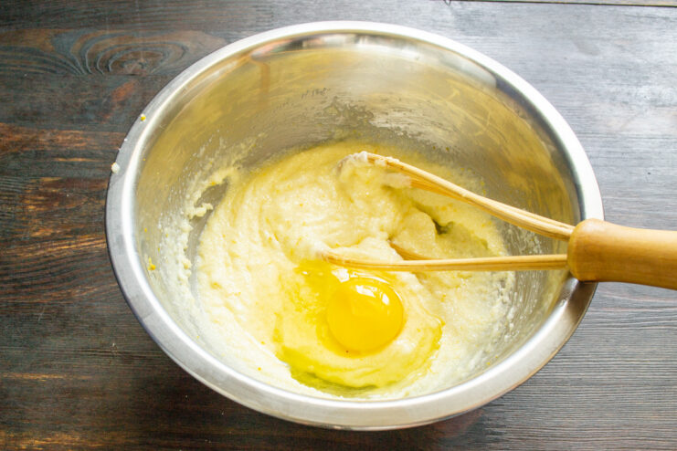 Incorporating eggs one by one into the batter. An egg being cracked into the butter and sugar mixture for the pound cake.