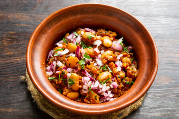 Serving Lobio with a Tangy Pickled Onion Garnish A bowl of white bean lobio being garnished with bright pink pickled red onions.