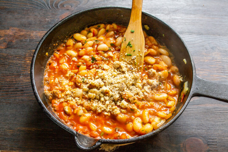 Incorporating Ground Walnuts for Creaminess and Flavor Ground walnuts being sprinkled into the skillet with the white bean lobio.