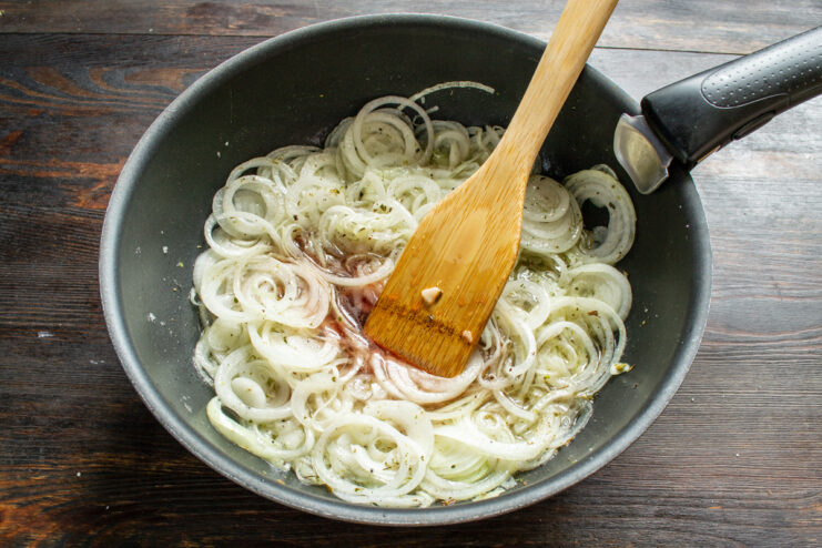 Cooking Onions with Seasonings Onions cooking with spices in a skillet for the first 10 minutes of the recipe.