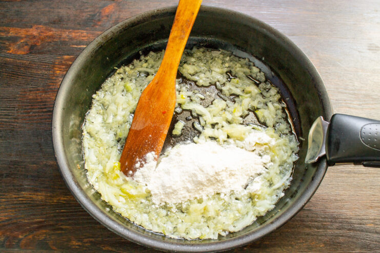Making a Roux with Flour and Onions Flour being stirred into sautéed onions in a skillet to make a roux.