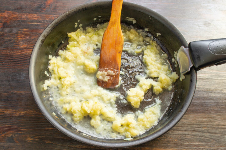 Gradually Adding Broth to Create a Smooth Sauce Chicken broth being whisked into the roux in a skillet to create a sauce base.