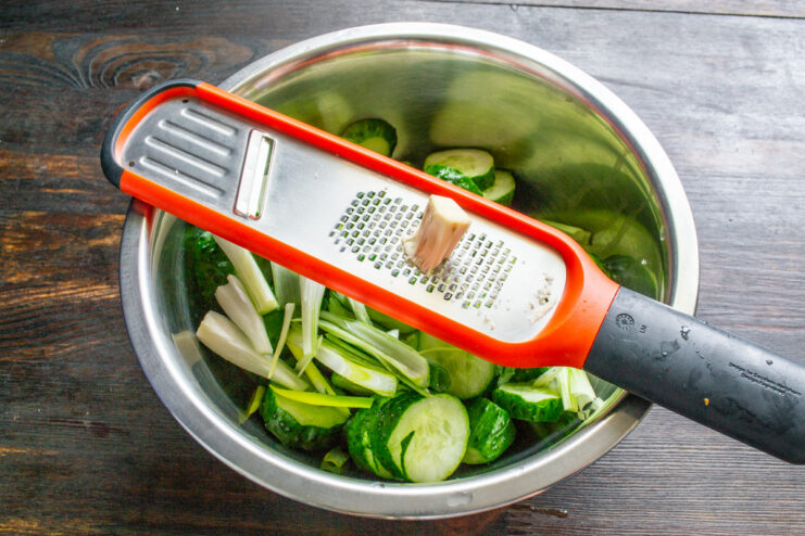 Grating Fresh Horseradish for a Spicy Kick A hand grating a fresh horseradish root on a fine metal grater.