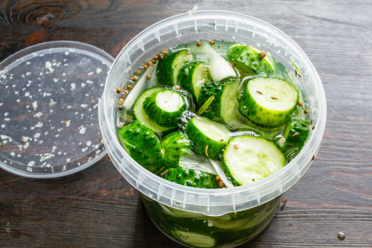 Covering the Cucumbers with Water to Start Fermentation Pouring cold filtered water from a pitcher into the jar of cucumbers.