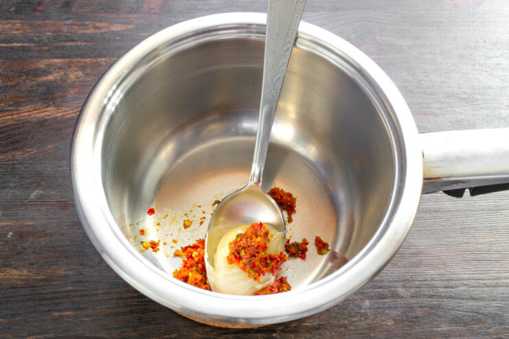 Making the Spicy-Sweet Marinade Base A saucepan with honey and red chili paste being added to start the marinade.