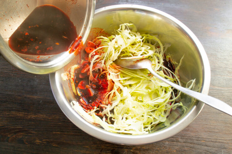 Combining Cabbage and Hot Marinade Pouring the hot, boiling marinade over the shredded cabbage in a bowl.