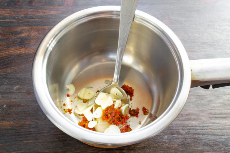 Preparing Garlic for the Marinade Thinly sliced garlic cloves on a cutting board for the cabbage marinade.