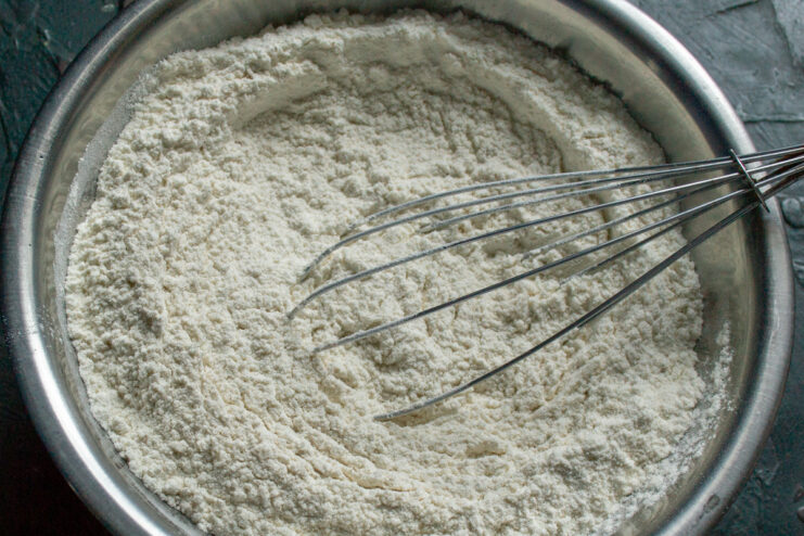 Mixing freshly ground spices with flour for the gingerbread dough. A bowl of flour with a mix of ground spices being added.