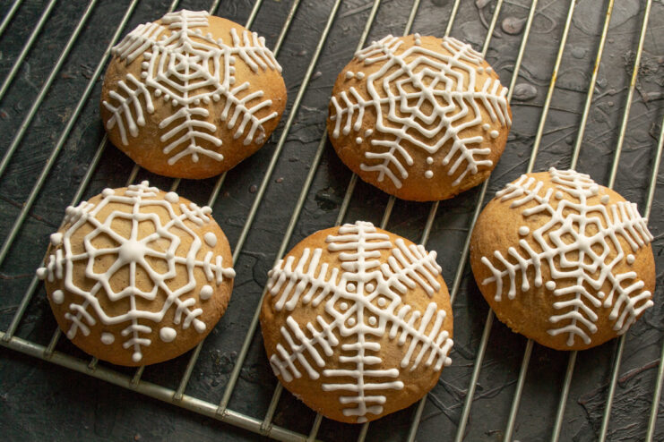 Allowing the royal icing on the gingerbread cookies to dry completely. Decorated gingerbread cookies with snowflake icing drying on a wire rack.