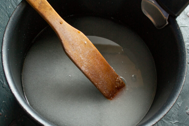 Making the sugar syrup base for the gingerbread dough in a saucepan. A saucepan on the stove with bubbling sugar syrup for the gingerbread recipe.
