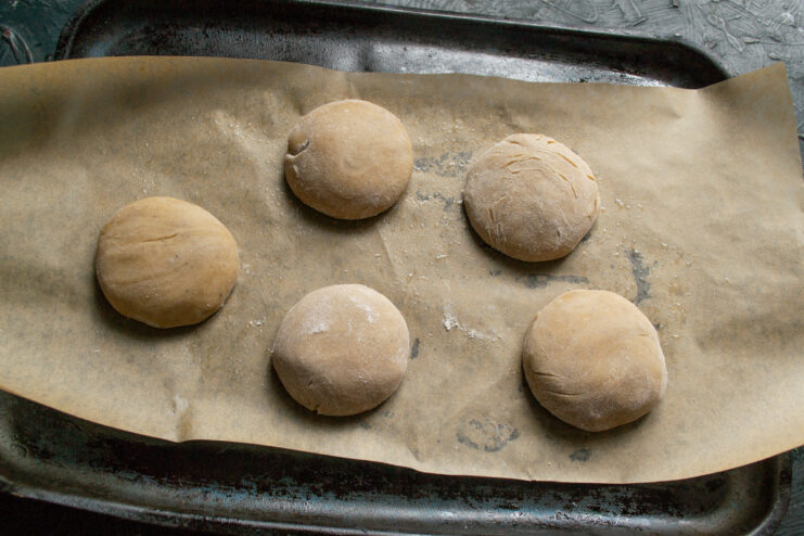 Arranging the gingerbread cookies on a baking sheet before baking. Shaped gingerbread dough balls arranged on a parchment-lined baking sheet.