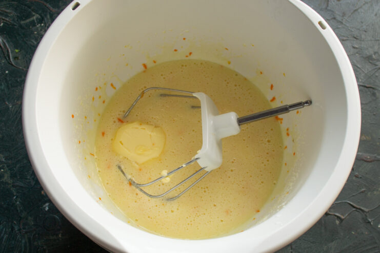 A bowl with wet ingredients for the almond cake being mixed with a hand mixer.