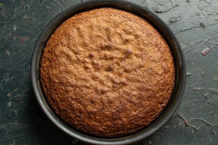 A freshly baked golden brown almond cake in its baking pan, just out of the oven.