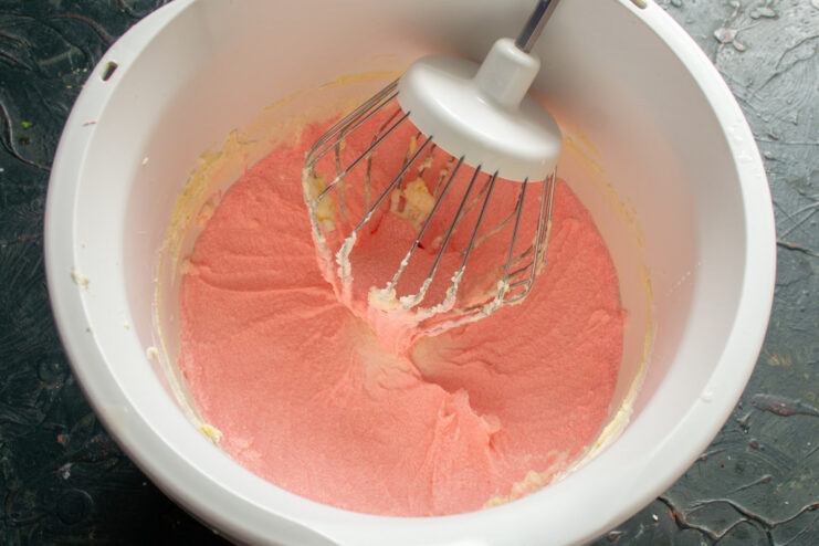 A bowl of creamy pink frosting made with mascarpone and heavy cream.
