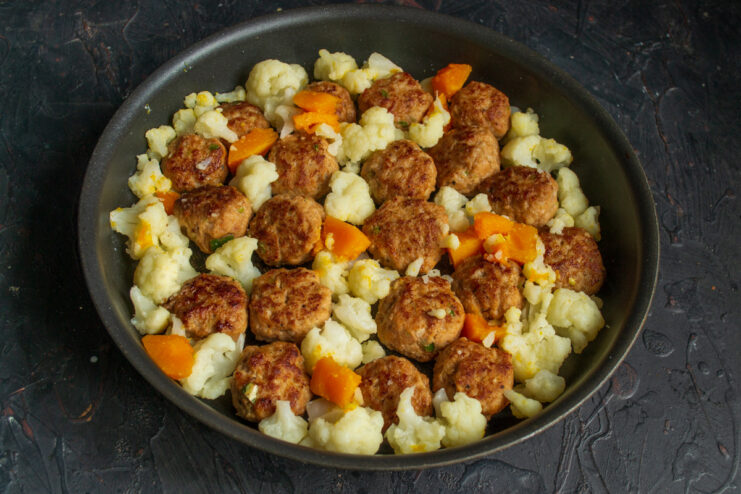 Assembling the Dish: Combining Seared Meatballs and Blanched Vegetables Seared meatballs and blanched vegetables arranged in a baking dish before going into the oven.