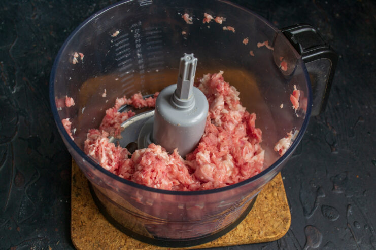How to Make Smooth Minced Meat in a Food Processor Pork and fat being processed into a fine mince inside a food processor bowl.