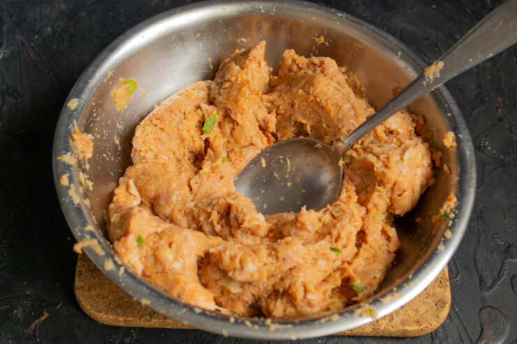 Mixing the Meatball Dough by Hand for Even Flavor Hands mixing the seasoned ground meat mixture in a bowl to combine all ingredients.