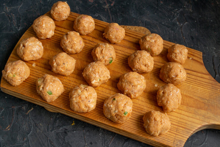 How to Form Perfect, Uniform Meatballs by Hand A person's wet hands shaping the ground meat mixture into a small, round meatball.
