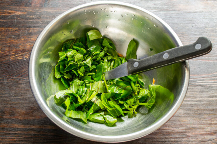 Fresh green basil leaves being picked from their stems.