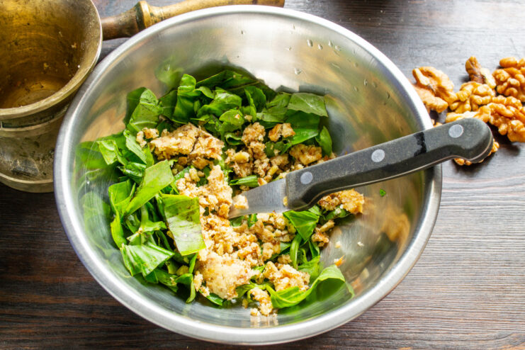 Walnuts being crushed in a stone mortar with a pestle.