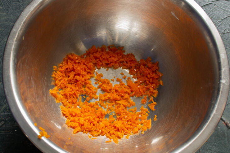 Step-by-step: How to prepare orange zest for muffins. Close-up of finely chopped orange zest on a cutting board.