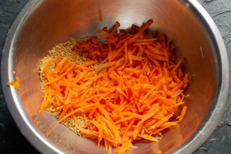 Preparing carrots for the muffin batter. Freshly grated carrots in a bowl, ready for the recipe.