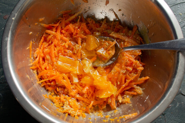 Adding citrus flavor: orange juice and segments. A bowl with muffin batter, with orange juice and segments being added.