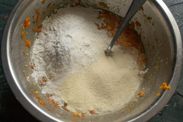 Mixing the dry ingredients for the muffins. Flour, semolina, and baking powder being added to the wet ingredients.
