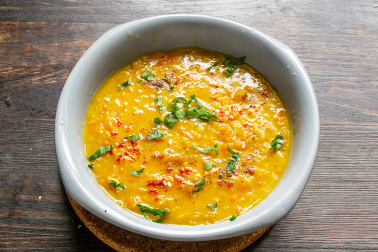 Serving the Hot Carrot and Lentil Soup with Croutons or Fresh Bread A finished bowl of carrot and lentil soup served hot, ready to be eaten with bread.