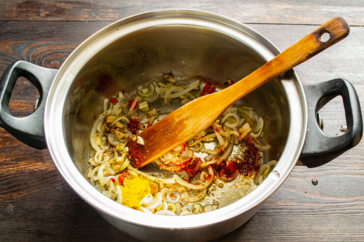 Adding Aromatic Spices for a Flavorful Soup Ground spices being added to the sautéing vegetables in a pot.