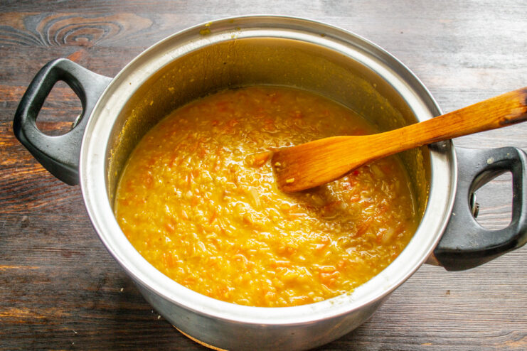 Simmering the Soup to Perfection for a Rich Flavor The carrot and lentil soup simmering in a covered pot on the stove.