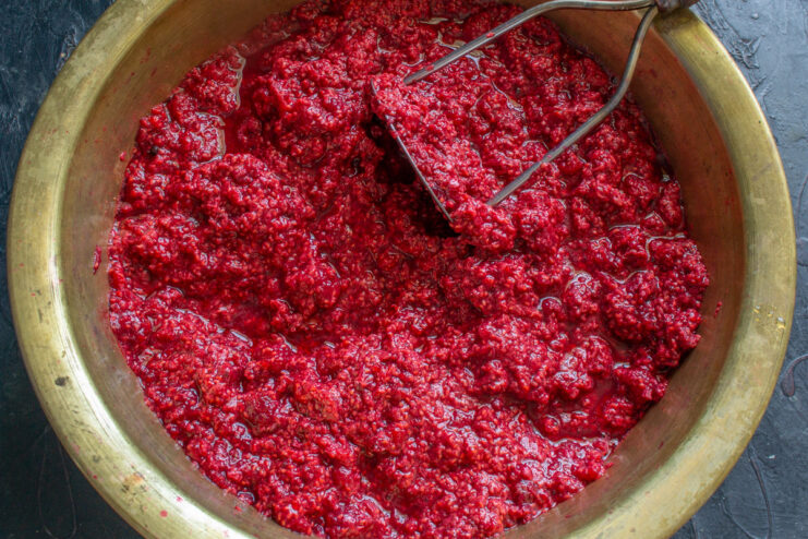 Starting the Raspberry Juice Infusion Process Prepared raspberries being added to a pot of hot water on a stove.