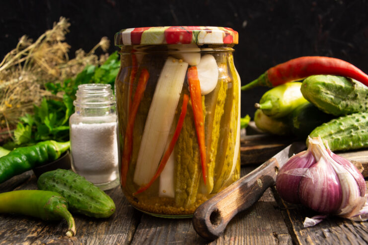 A jar of freshly pickled cucumbers and zucchini with chili and dill, ready for preserving.
