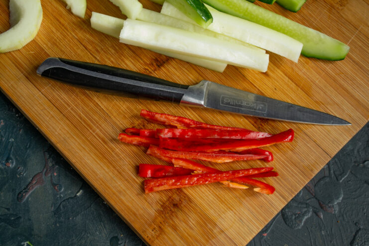 Adding a Spicy Kick: Slicing Chili for Pickles A red chili pepper being sliced into long, thin strips to be added to the pickling jar.